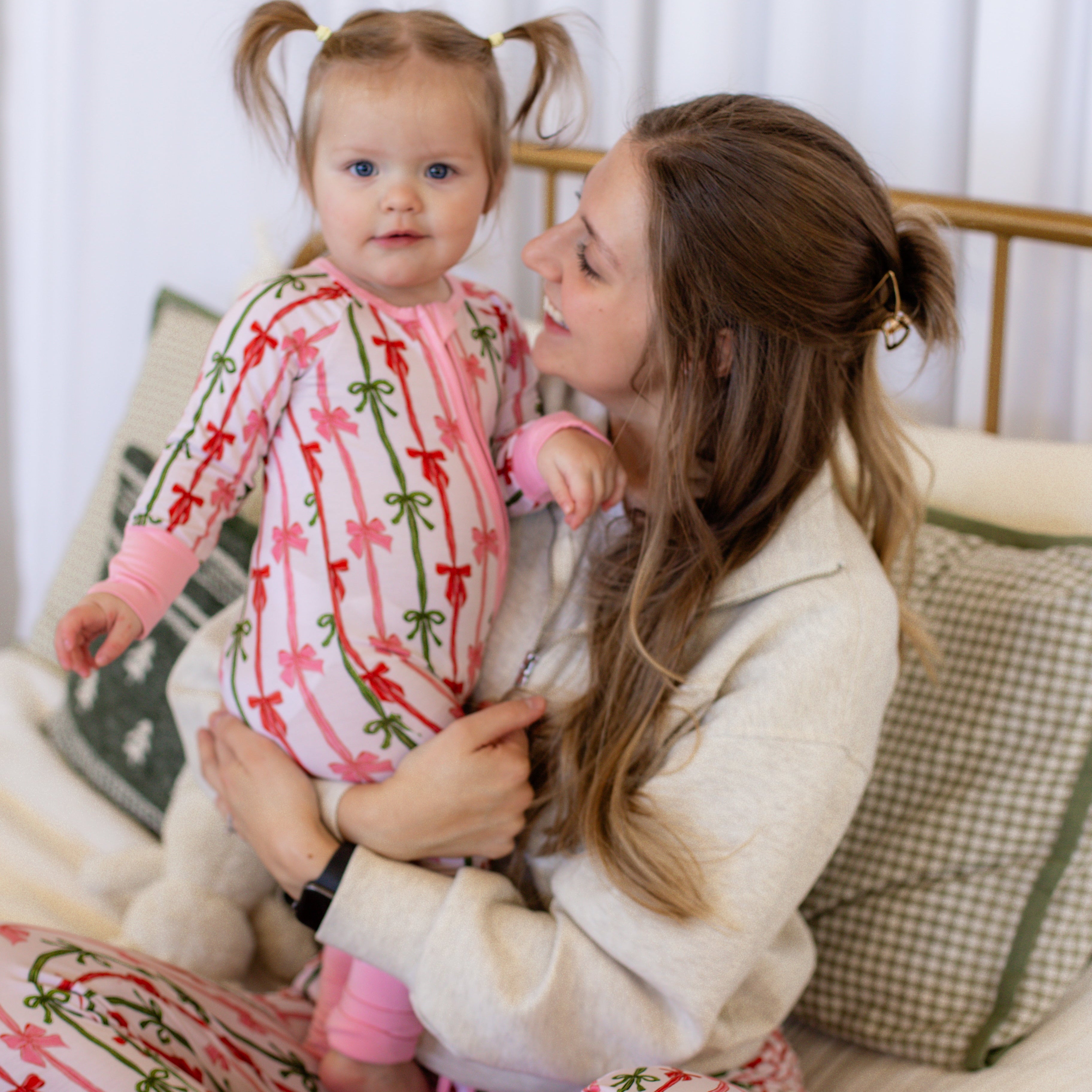 Woman and child in matching pajamas sitting on a couch.